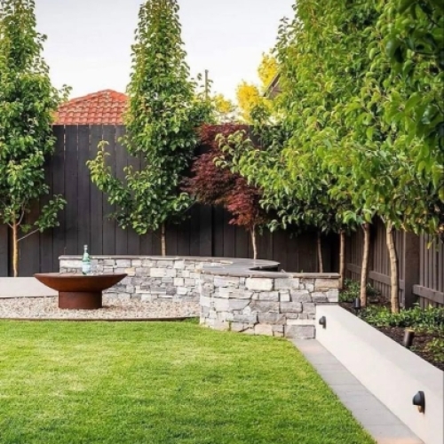 Belægning i have med fliser og støttemur udført i moderne haveanlæg