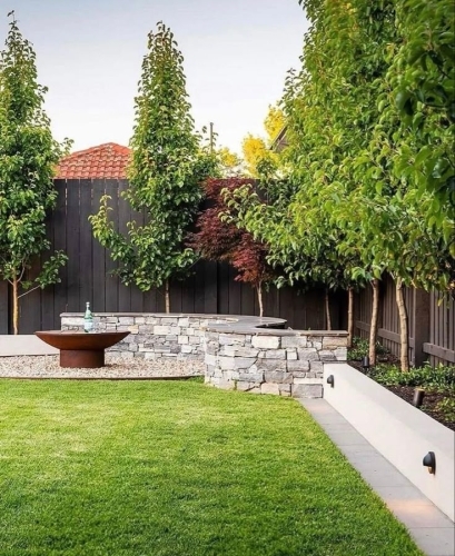 Belægning i have med fliser og støttemur udført i moderne haveanlæg