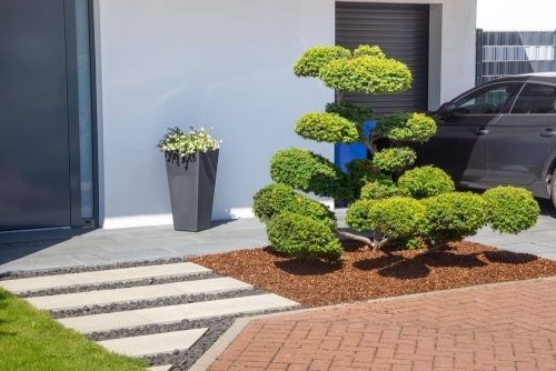 Udendørs belægning med fliser ved moderne indgangsparti og haveanlæg