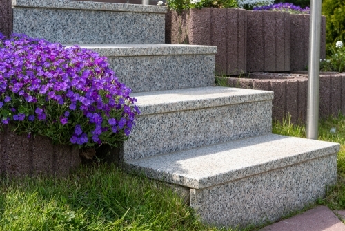 Udendørs belægning med fliser og trapper udført som del af støttemur og haveanlæg